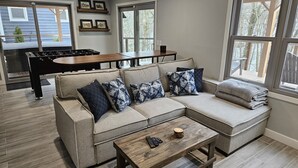 A living room with a sectional sofa, a coffee table, and a foosball table.