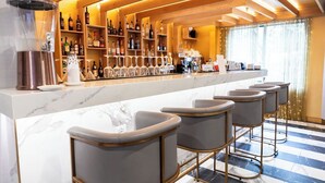 Zona de bar con mostrador de mármol, taburetes y estantes llenos de botellas de licor.