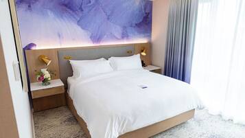 A hotel room with a large bed, a nightstand with a lamp, and a wall-mounted artwork.
