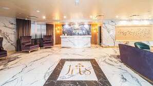 Vestíbulo de hotel con una recepción, asientos cómodos y piso de mármol.