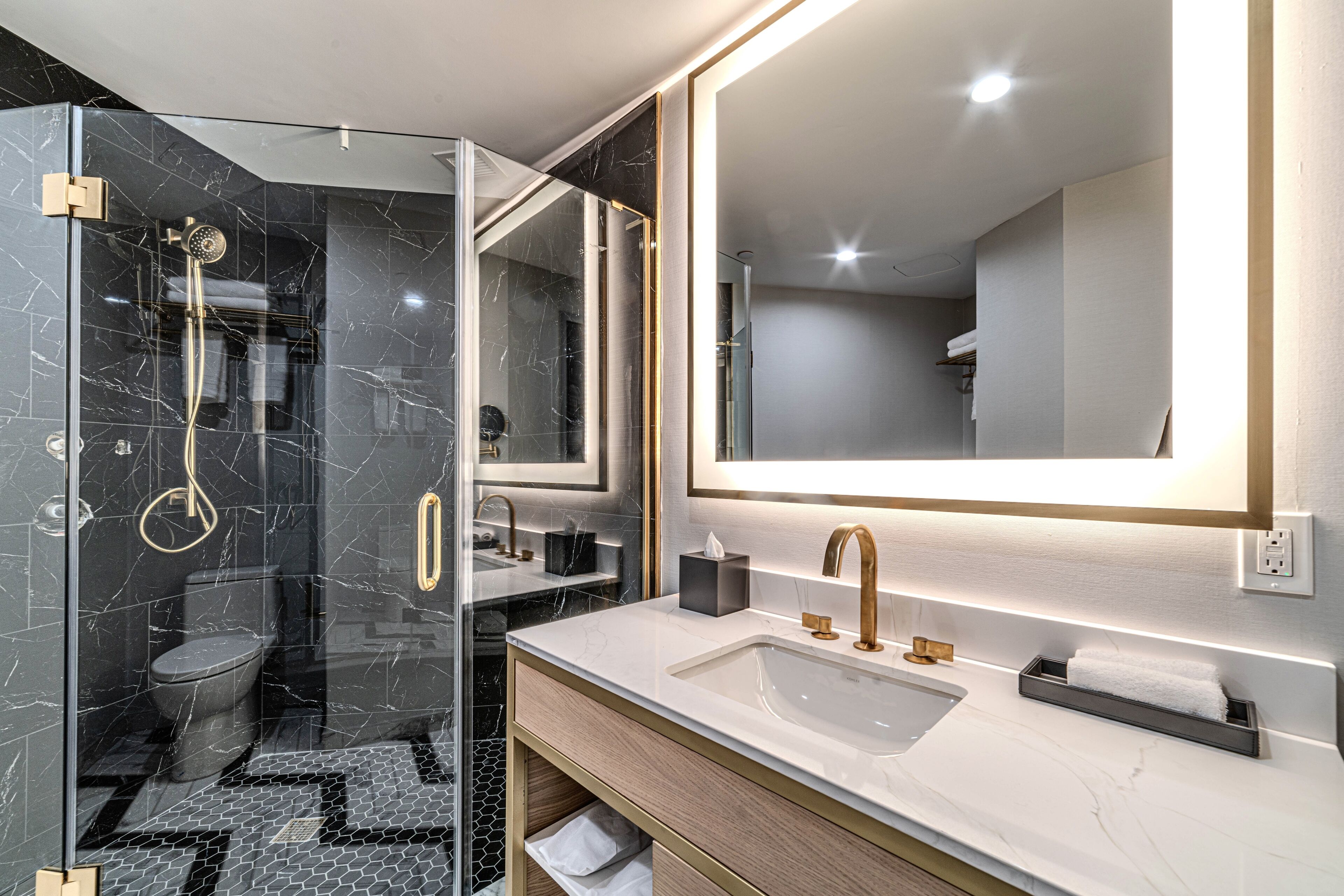 A modern bathroom with a glass-enclosed shower, a large mirror, and a vanity with a sink and towel rack.