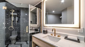 A modern bathroom with a glass-enclosed shower, a large mirror, and a vanity with a sink and towel rack.