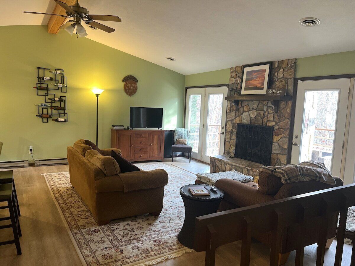 Un salon avec une cheminée, un téléviseur et un ventilateur de plafond.