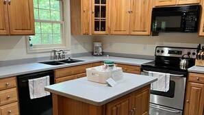 Una cocina con armarios de madera, estufa de acero inoxidable, microondas y lavavajillas.