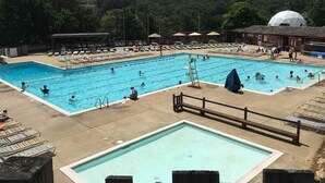 A large outdoor swimming pool with multiple lanes, surrounded by lounge chairs and umbrellas. - Lovely Views - Top of the Mountain - Foosball & Pool Table - Screened in Porch (McGaheysville)