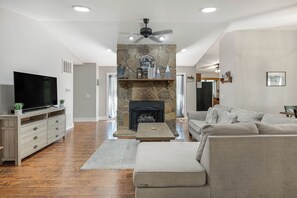 Una sala de estar con chimenea de piedra, televisor de pantalla plana, sofá y mesa de centro.