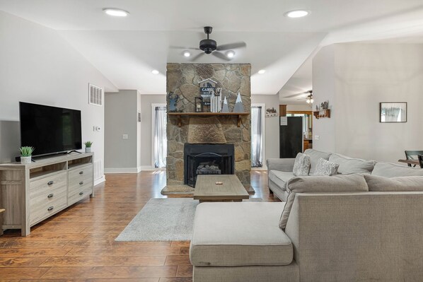 A living room with a stone fireplace, a flat-screen TV, a sofa, and a coffee table.
