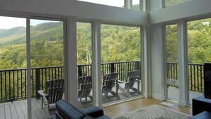 A spacious balcony with a view of a forested hillside, furnished with chairs and a sofa. - Stunning Views and Tastefully Decorated; Middle of Mtn; Work Space; Games & WiFi (McGaheysville)