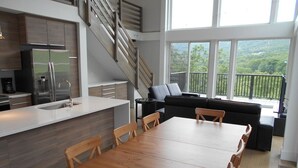 A modern kitchen with a wooden dining table and chairs, a built-in stove, and a large window overlooking a balcony. - Stunning Views and Tastefully Decorated; Middle of Mtn; Work Space; Games & WiFi (McGaheysville)