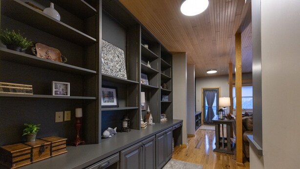 Une cuisine moderne avec des meubles de rangement aux couleurs sombres, un plan de travail en bois et une vue sur la salle à manger.