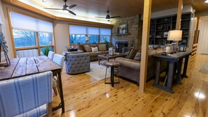 Un salon spacieux doté d’une cheminée, de parquet et de grandes fenêtres.
