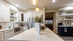 Une cuisine moderne avec des meubles blancs, un îlot central et un luminaire suspendu.