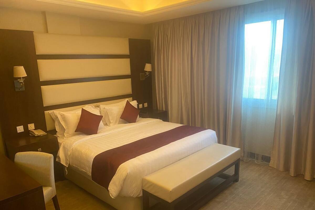 A hotel room with a large bed, a desk, and a chair.