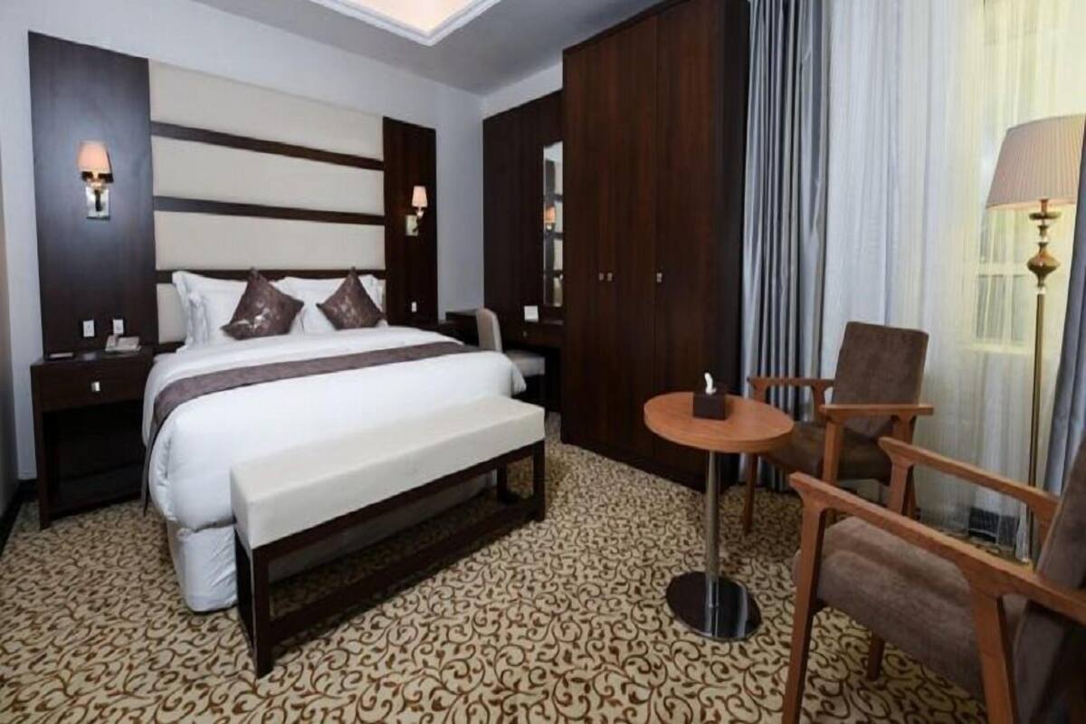 A hotel room with a large bed, a desk, a chair, and a small table.
