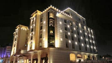 A multi-story hotel with illuminated windows and balconies, featuring a central courtyard with arches.
