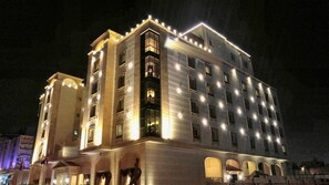 Un hotel de varios pisos con ventanas e balcones iluminados, que cuenta con un patio central con arcos.