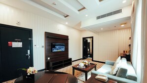 A hotel room with a flat-screen TV, a sofa, a coffee table, and a desk with a telephone. - Verta Hotel Qouraish (Jeddah)