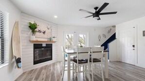 Une cuisine moderne dotée d’une cheminée, d’une table à manger avec des chaises et d’un ventilateur de plafond.