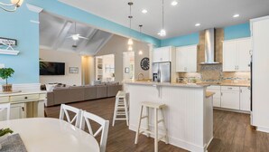 Une cuisine moderne dotée d’un îlot central, de meubles blancs et d’un coin repas avec une table et des chaises.