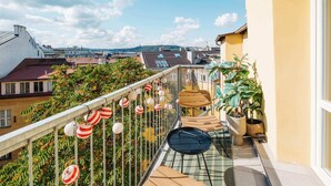 A balcony with a view of the city, potted plants, and striped lanterns. - TurnKey | Angelo Roma Studio – Cozy Balcony (Praha 2)
