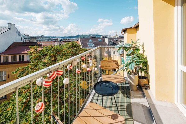 A balcony with a view of the city, potted plants, and striped lanterns. - TurnKey | Angelo Roma Studio – Cozy Balcony (Praha 2)
