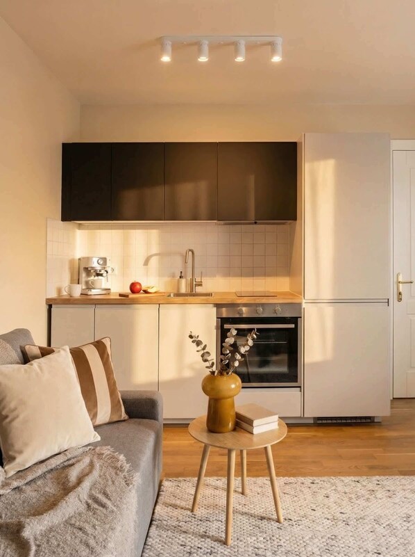 A modern kitchen with dark cabinets, a white countertop, and a built-in oven. - TurnKey | Angelo Roma Studio – Cozy Balcony (Praha 2)