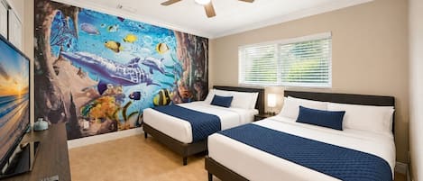 A hotel room with two beds, a ceiling fan, a mural of marine life, and a window with blinds.