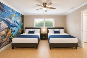 A bedroom with two beds, a ceiling fan, a window with blinds, and a mural of marine life on the wall.