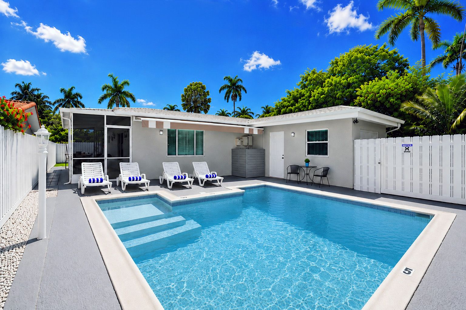 Une piscine avec des chaises longues, un patio couvert et une clôture blanche.