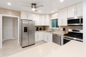 A modern kitchen with stainless steel appliances, white cabinetry, and a built-in dishwasher. - First-Class Villa in Hollywood Lakes Heated Pool (Hollywood)