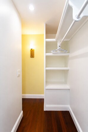 A narrow hallway with a wooden floor, a white closet with shelves, and a wall-mounted light fixture. - First-Class Villa in Hollywood Lakes Heated Pool (Hollywood)