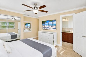 A bedroom with two beds, a ceiling fan, a dresser, and a bathroom visible through an open door.