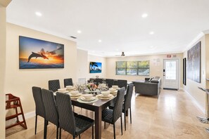 A dining area with a table set for six, chairs, and a painting of dolphins on the wall.