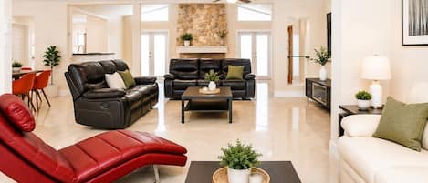 A spacious living area with leather sofas, a red recliner, a coffee table, and a fireplace.