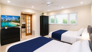 Habitación de hotel con dos camas, televisión, armario y ventana con persianas.