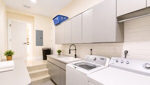 Una cocina moderna con lavadora y secadora integradas, un lavabo y una encimera.
