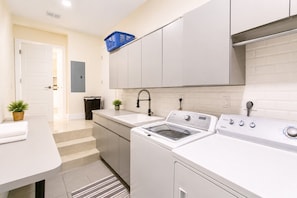 Una cocina moderna con lavadora y secadora integradas, un lavabo y una encimera.