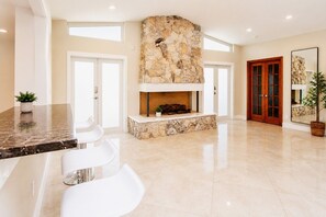 A spacious living area with a stone fireplace, white chairs, and a large mirror. - Amazing Villa Walk to Beach Heated Pool & Jacuzzi (Hollywood)