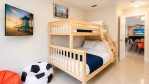 Habitación con literas, un cuadro de un paisaje urbano, un balón de fútbol y una puerta que da a un comedor.