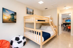 Habitación con literas, un cuadro de un paisaje urbano, un balón de fútbol y una puerta que da a un comedor.