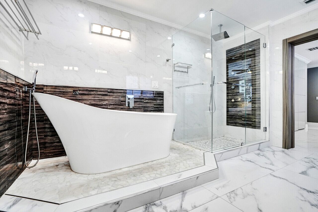 A modern bathroom with a freestanding bathtub, a glass-enclosed shower, and marble flooring.
