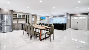 A modern kitchen with a dining area, stainless steel appliances, and a large window. - Spectacular 5BR/5BA Villa in Hollywood Lakes (Hollywood)