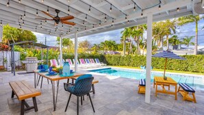 An outdoor pool area with a covered patio, seating, and a view of the pool. - Ultimate Luxury 5BR Villa near Hollywood Beach (Hollywood)