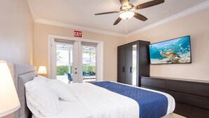 A hotel room with a bed, a ceiling fan, an exit sign, a TV, and a view of the outdoors. - Ultimate Luxury 5BR Villa near Hollywood Beach (Hollywood)