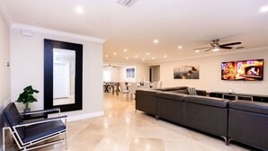 A modern living room with a sectional sofa, a black leather chair, and a flat-screen TV mounted on the wall. - Ultimate Luxury 5BR Villa near Hollywood Beach (Hollywood)
