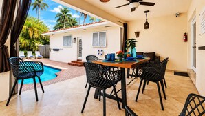 Zona de comedor junto a la piscina con mesa, sillas y ventilador de techo.
