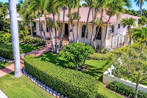 A house with a red-tiled roof, surrounded by palm trees and a well-maintained garden.
