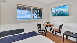 Una camera d'albergo con un letto, un tavolino con sedie, una televisione e una finestra con vista sulla città.