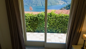 A room with a sliding glass door leading to a balcony with a view of a lake and mountains. - Villa Rosa - My Home in Como (Muronico)