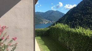 A view from a balcony overlooking a lake, surrounded by mountains and a well-maintained hedge. - Villa Rosa - My Home in Como (Muronico)